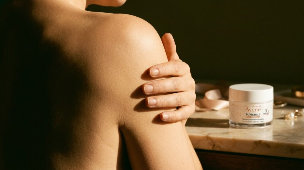 Woman's hand on shoulder in warm golden light representing self-care and pregnancy safe skincare journey