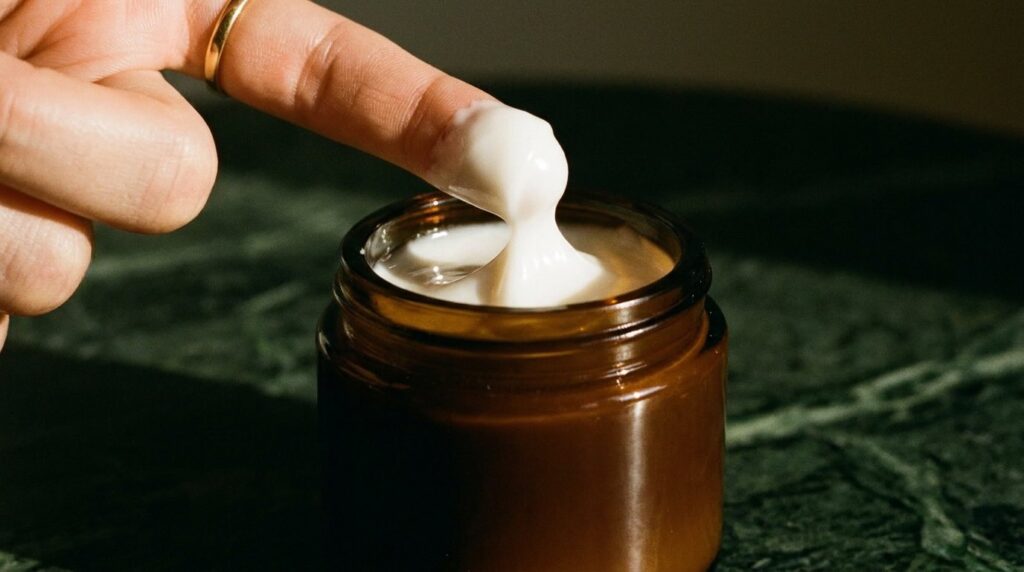 Rich La Mer cream texture being scooped from jar showing luxurious ritual in warm editorial light